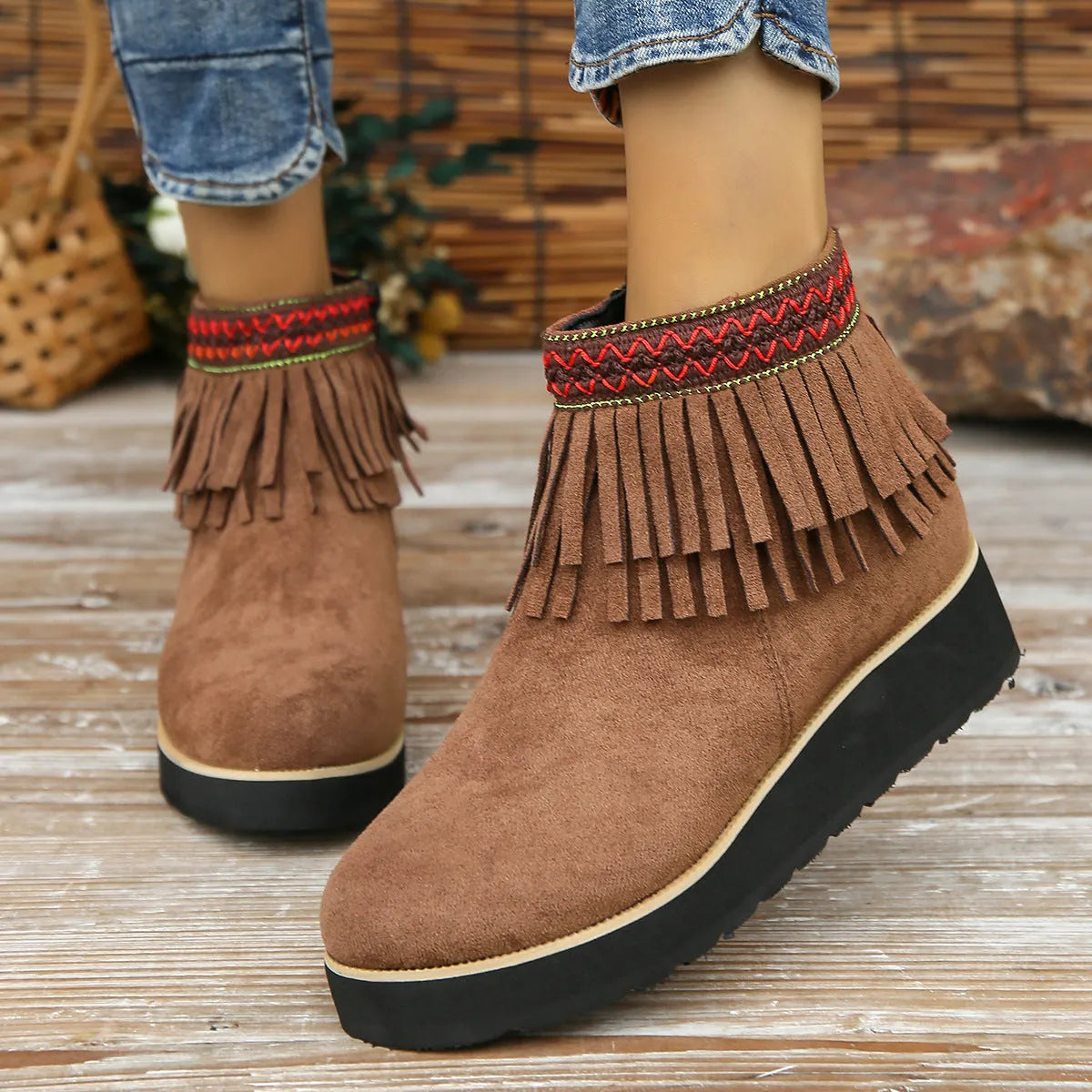 Women's ankle boot in suede with wedge heel, side zipper, and tassel detail on a dark background.