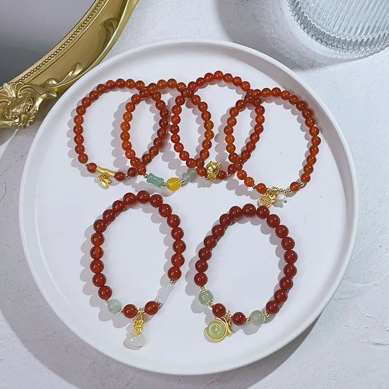 Handmade red agate bracelet with dragon motif and lucky charm beads.