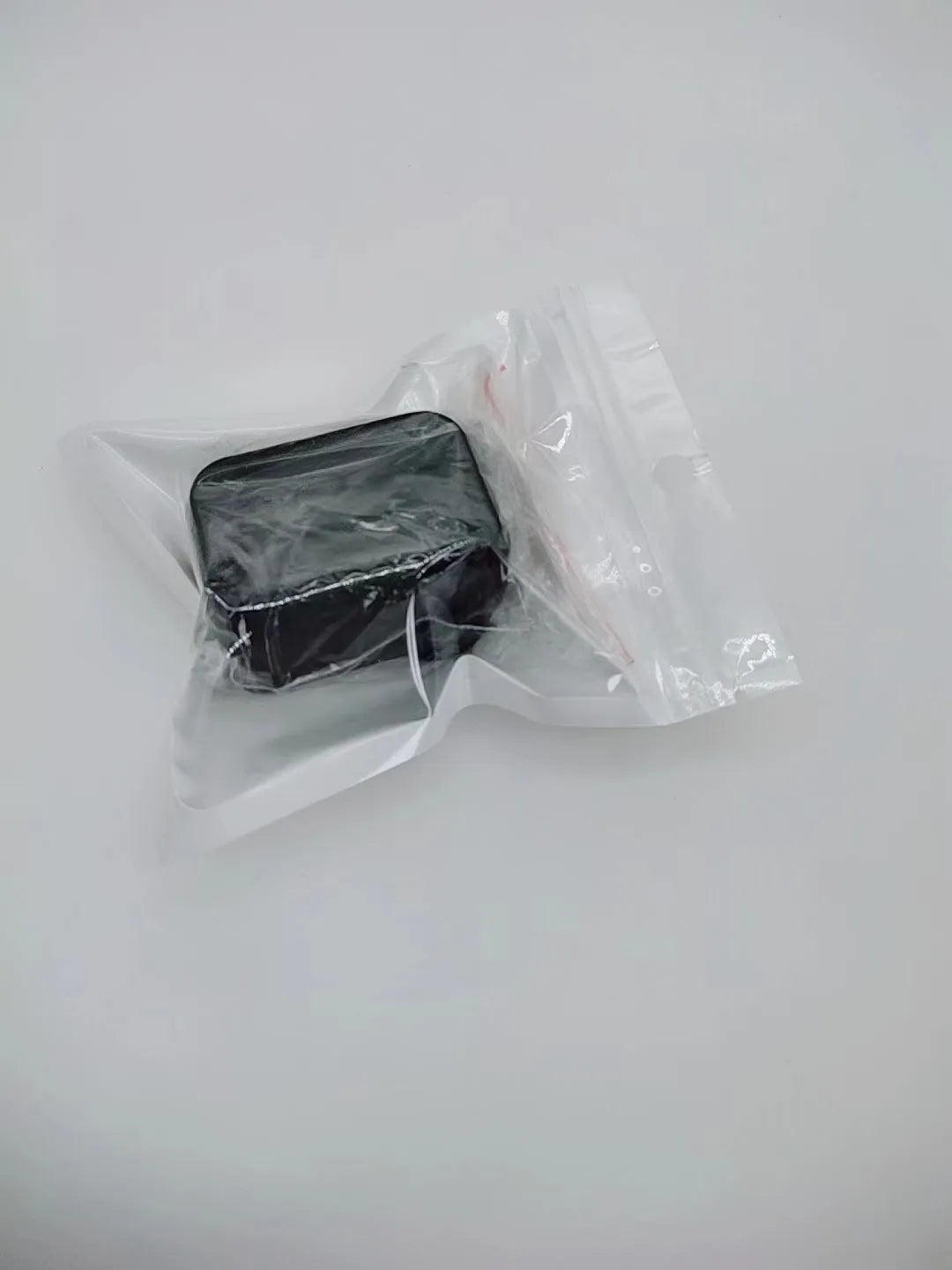 Black plastic ABS seat belt lock catch clamped onto a car seat belt buckle, side view