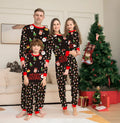 Family wearing matching red plaid Christmas pyjamas, including parents, children, baby, and dog.
