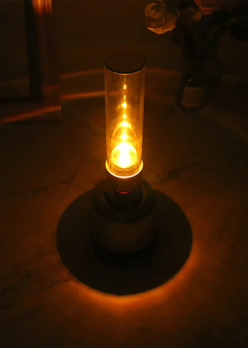 White silver Bluetooth speaker with integrated candlelight atmosphere night light on a table.