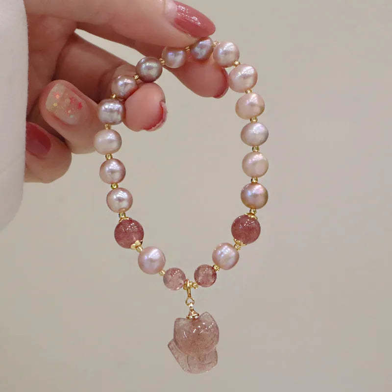 Women's natural freshwater pearl bracelet with light pink pearl, strawberry quartz, and fox charm on white background