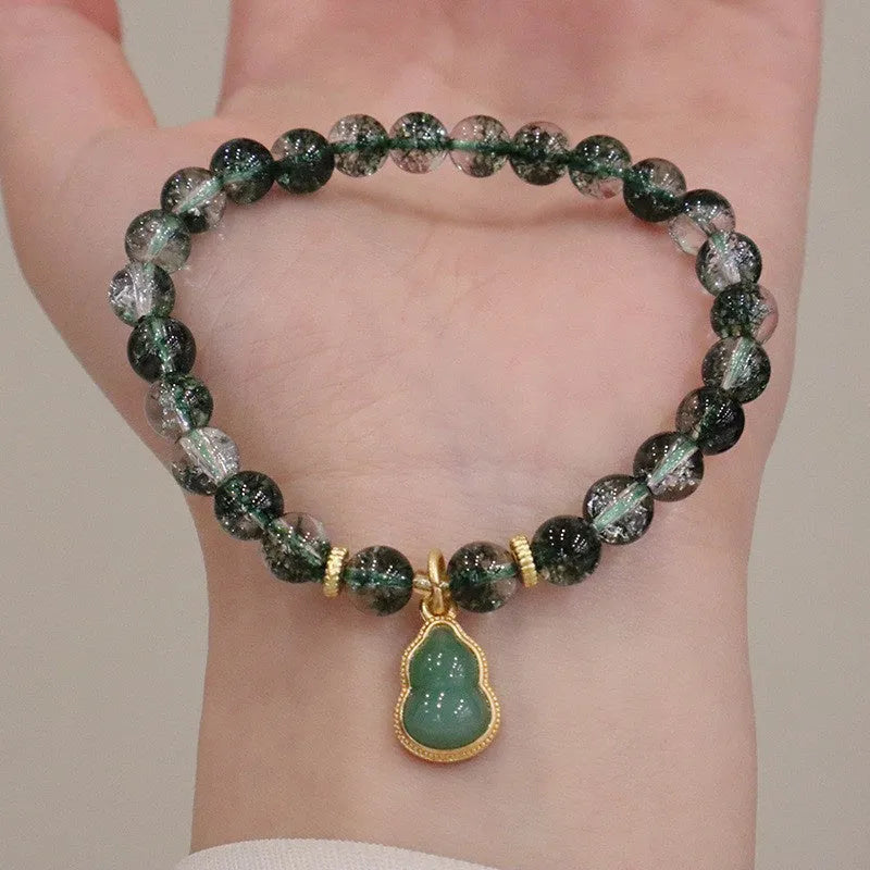 Heart-shaped green phantom quartz crystal bracelet with pearl accents on a neutral background
