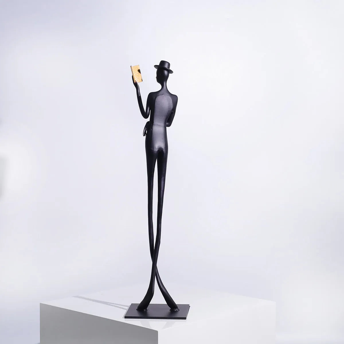 Black cast aluminium reading woman sculpture on desk, modern minimalist design