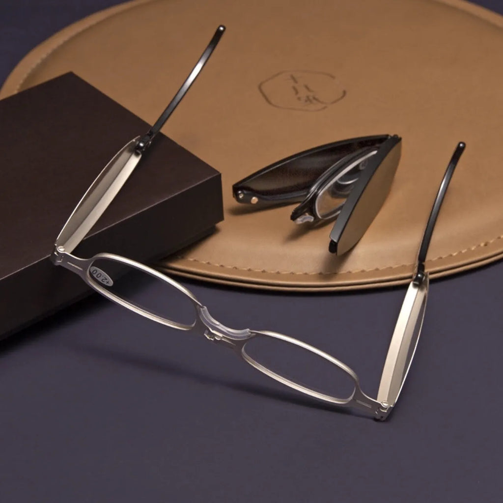 Folding presbyopic glasses in black frame showing collapsed and open positions with retro ring detailing