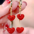 Red heart-shaped long earrings for women made of alloy with an electroplated finish, shown against a neutral background.