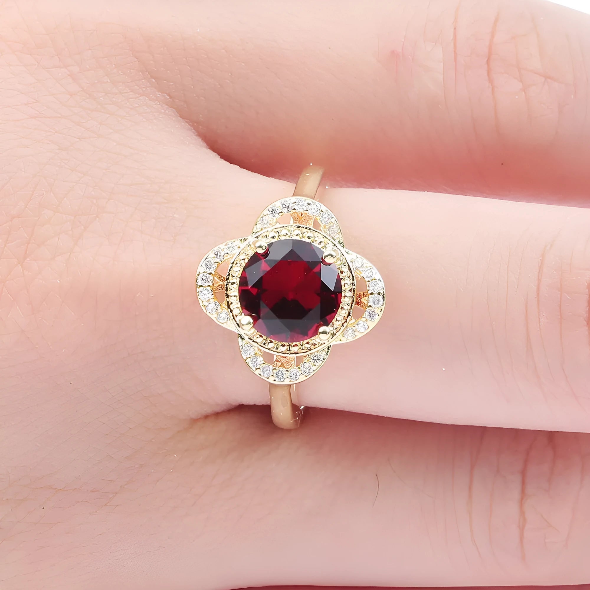 Close-up of a fruit-shaped copper ring with an electroplated finish and an inlaid zircon, shown on a hand.