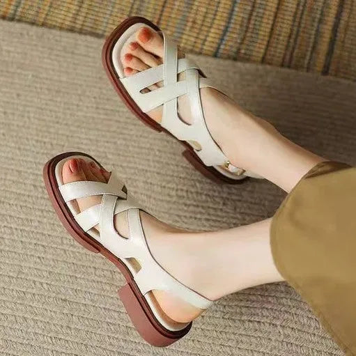 Glossy black patent leather women's sandals with square toe and winding tape closure on a rubber sole.