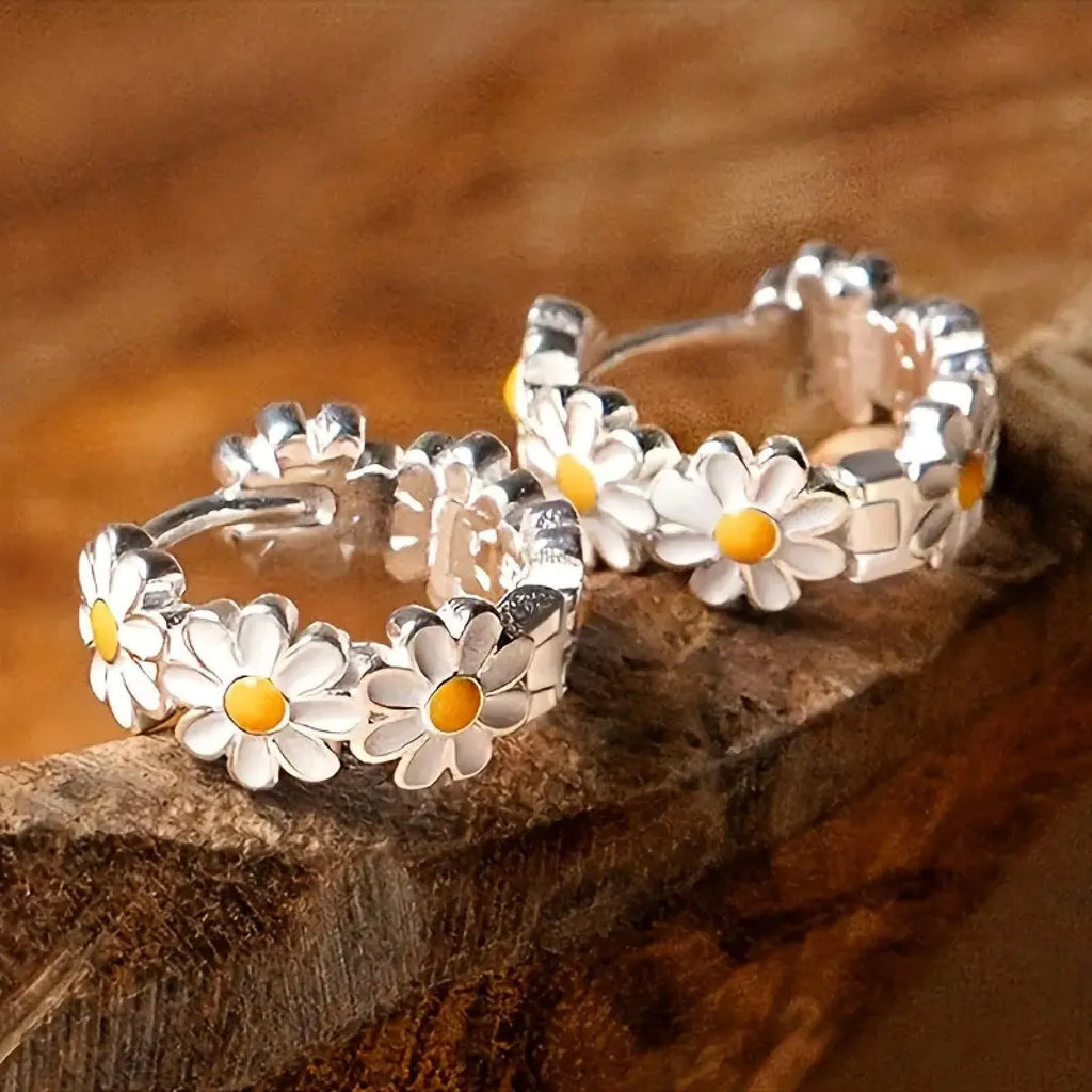 A pair of white daisy flower design ring earrings with a platinum-inlaid gemstone accent.