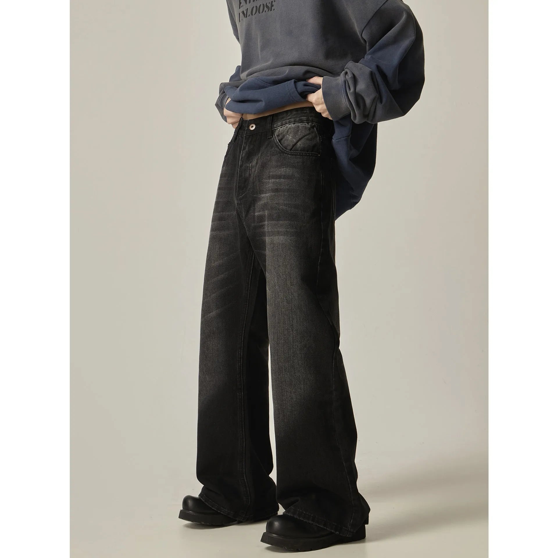 Man's black loose-fit straight-leg jeans with a retro style on a plain background.
