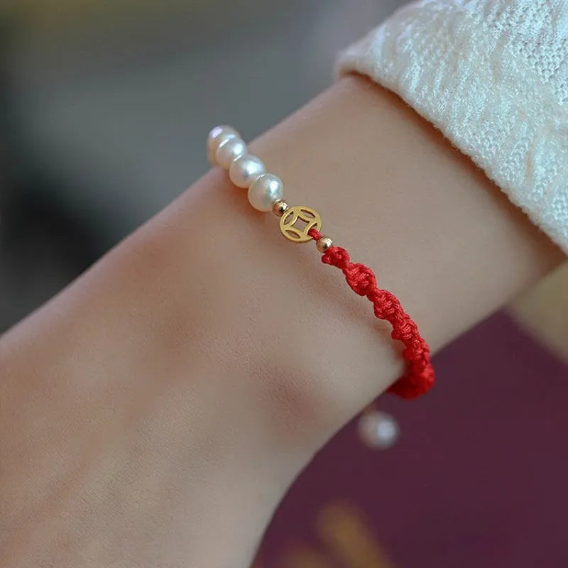 Women's pearl braided red rope bracelet with 14K gold plated fu character charm in geometric shape on white background