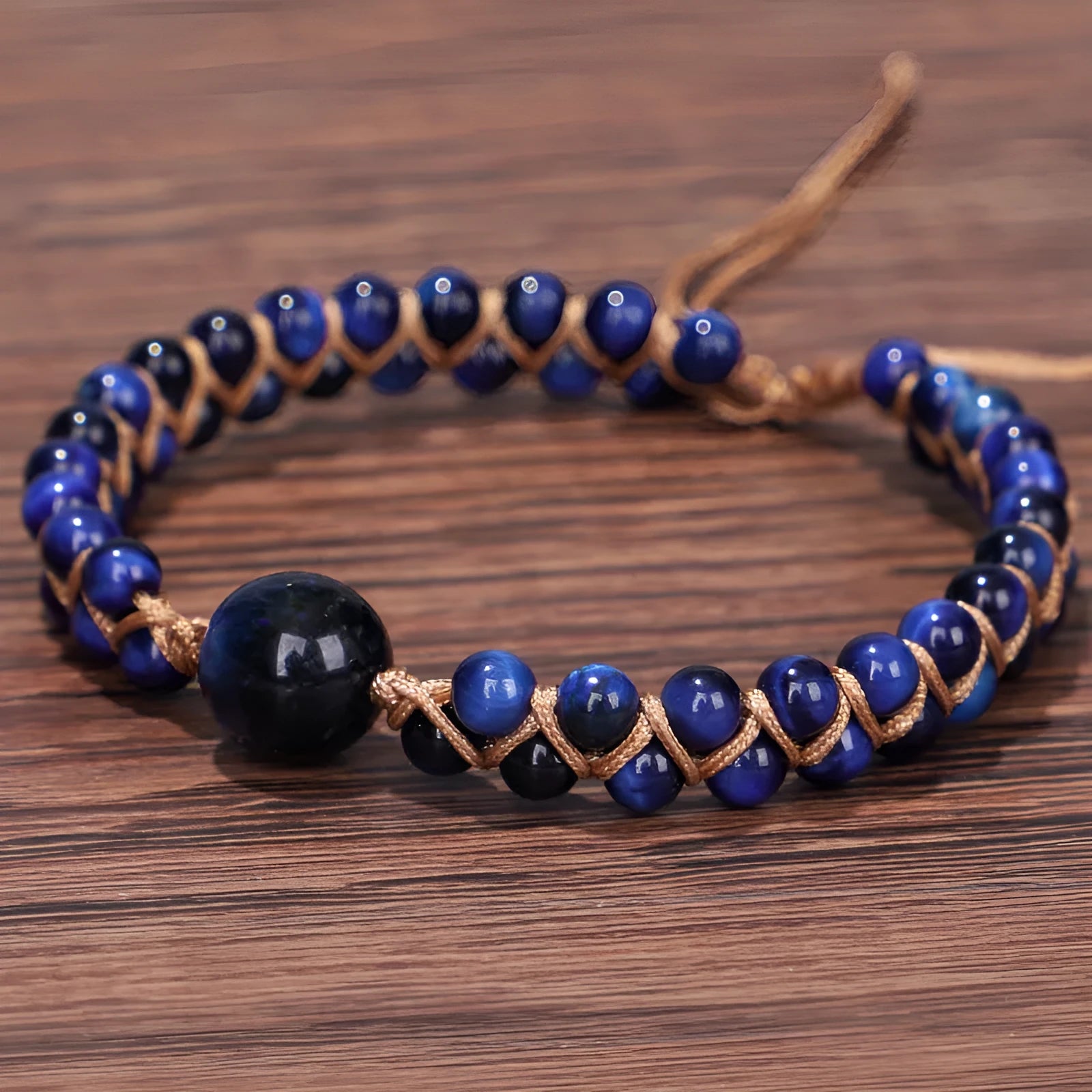 Handmade woven geometric pull bracelet with blue Tigereye stone beads on a wrist.