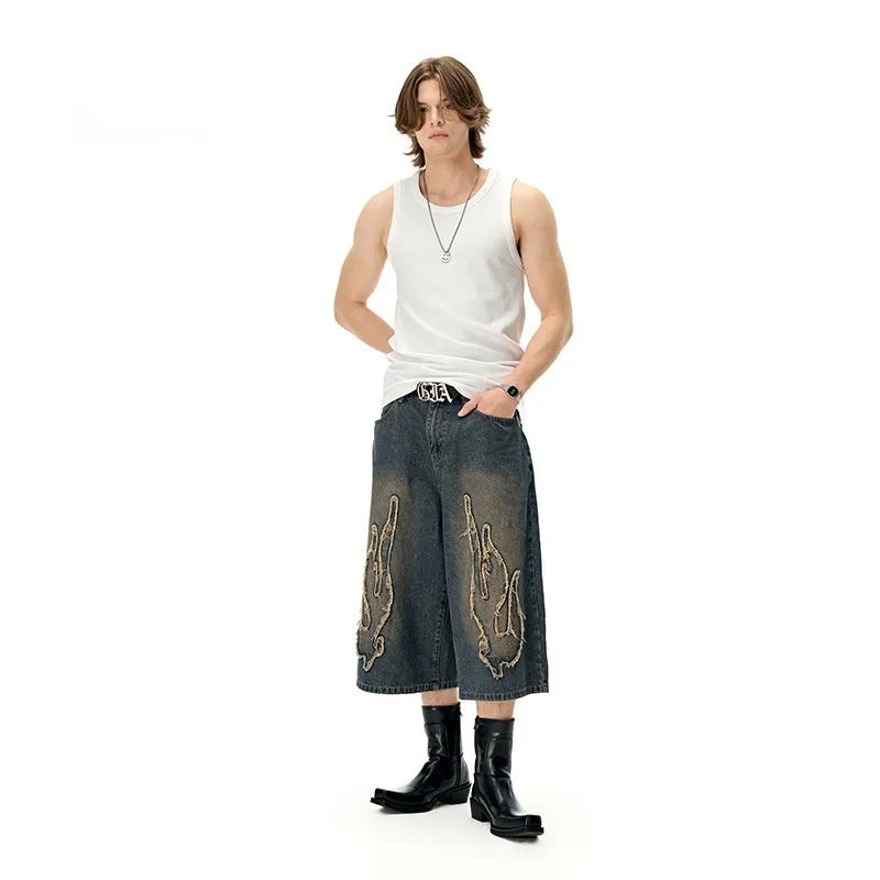 Men's black denim shorts with cropped flame embroidery patch on leg, straight cut.