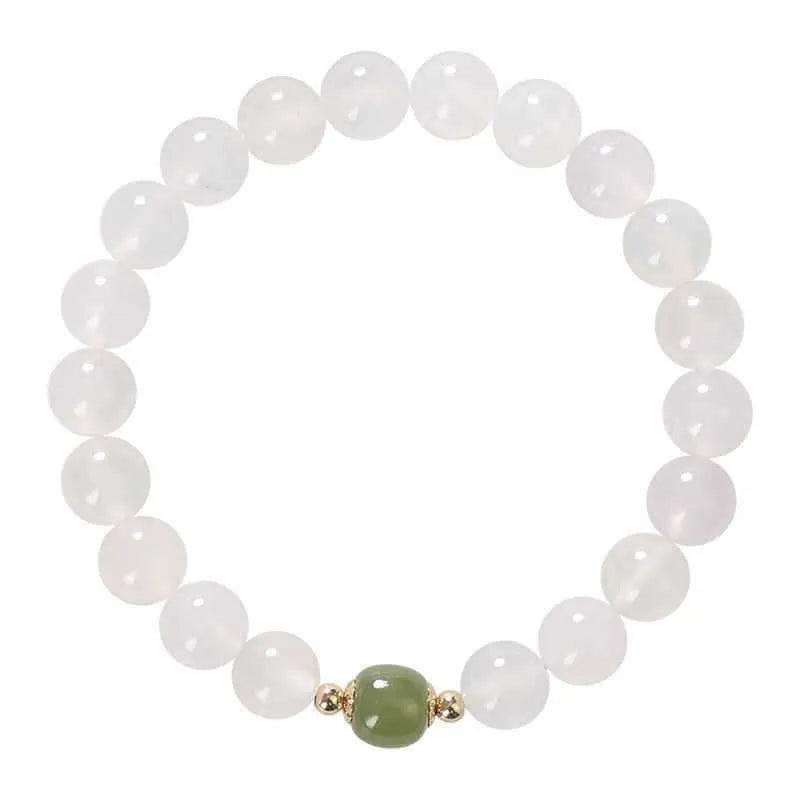 Handmade white agate and cinnabar bracelet with letter charms on a wrist.