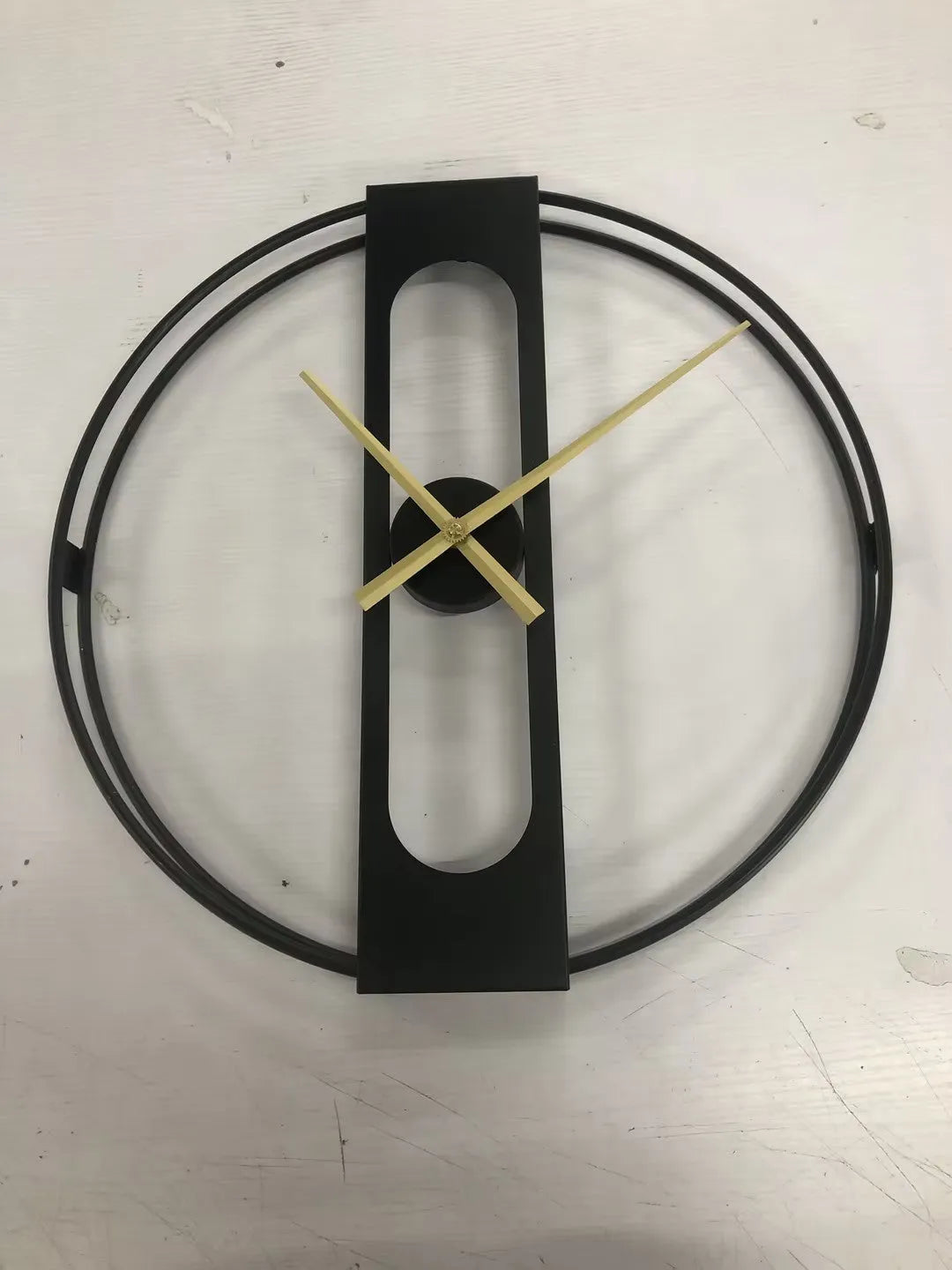 Round metal wall clock with 50 cm diameter in black or gold finish on a plain wall