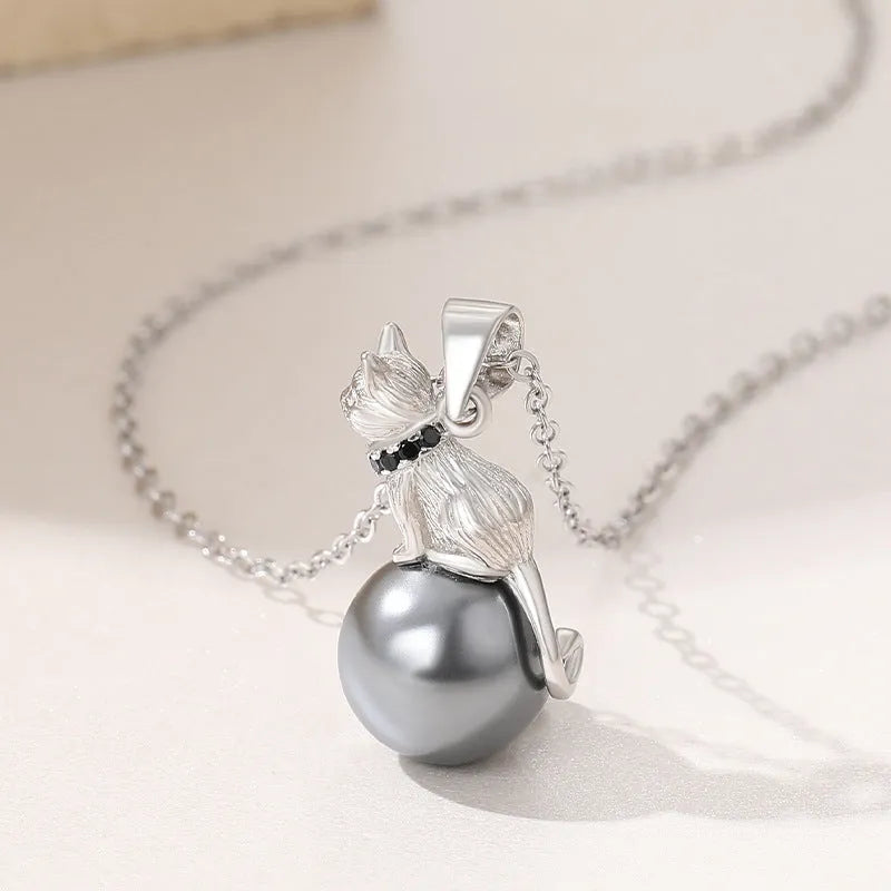 Close-up of a sterling silver cat pendant necklace on a dark background, showing the detailed charm.