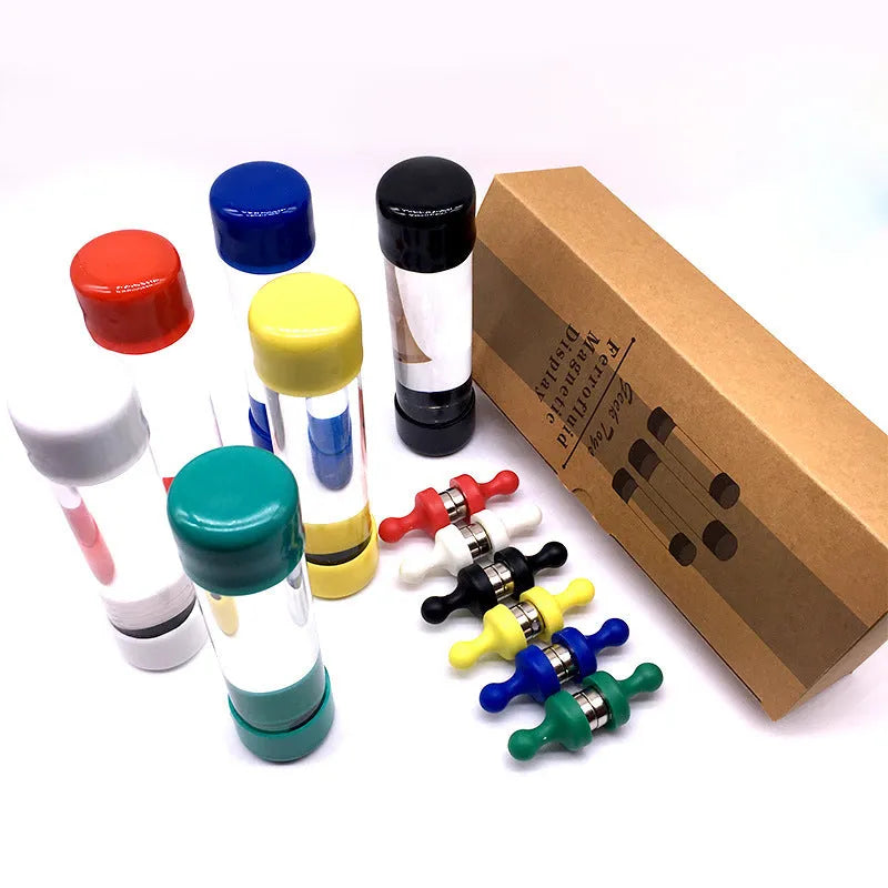 Magnetic fluid toy in a glass bottle with red ferrofluid and two black magnets on a white surface