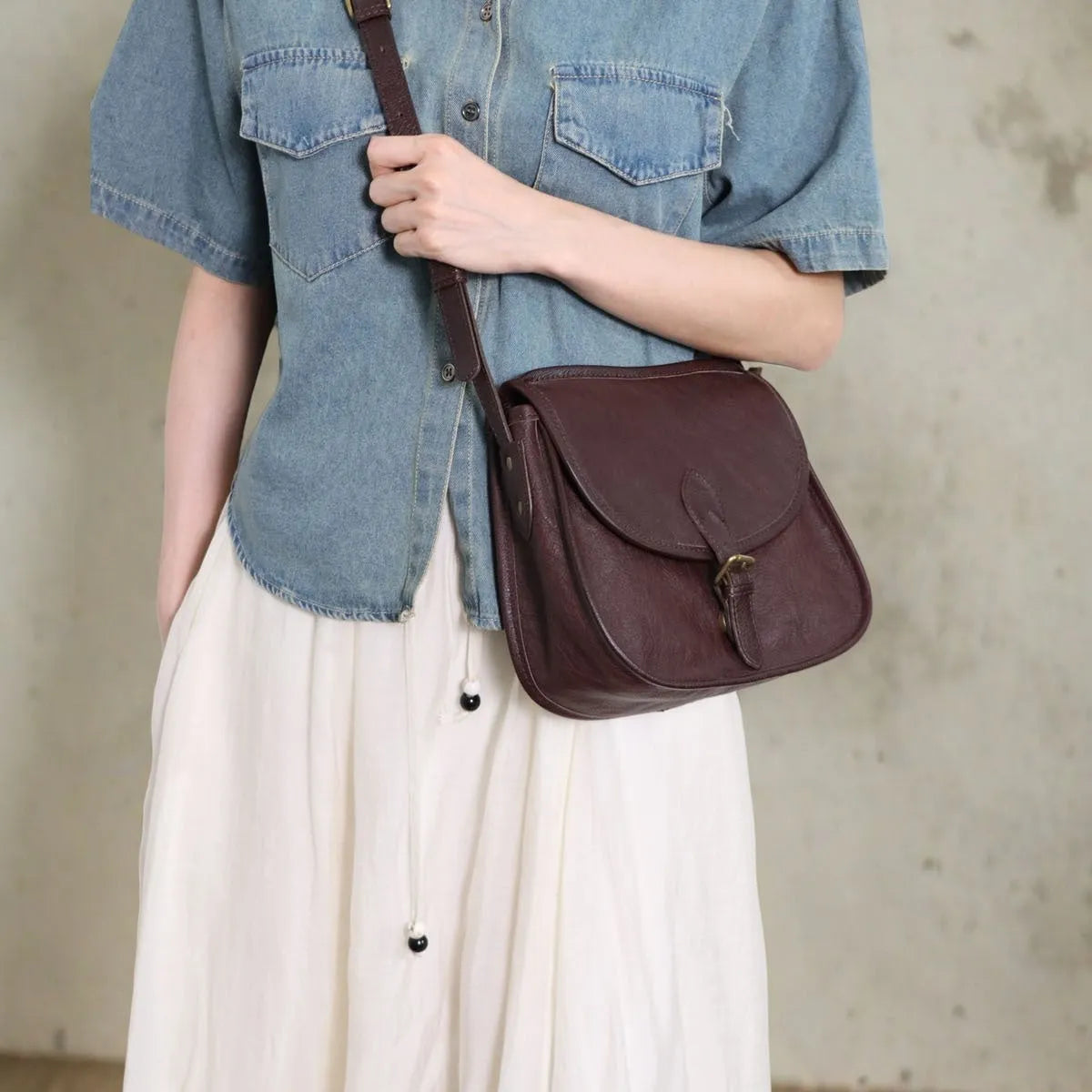 Genuine leather messenger bag in brown, soft shell shape with flap closure and visible sewing detail