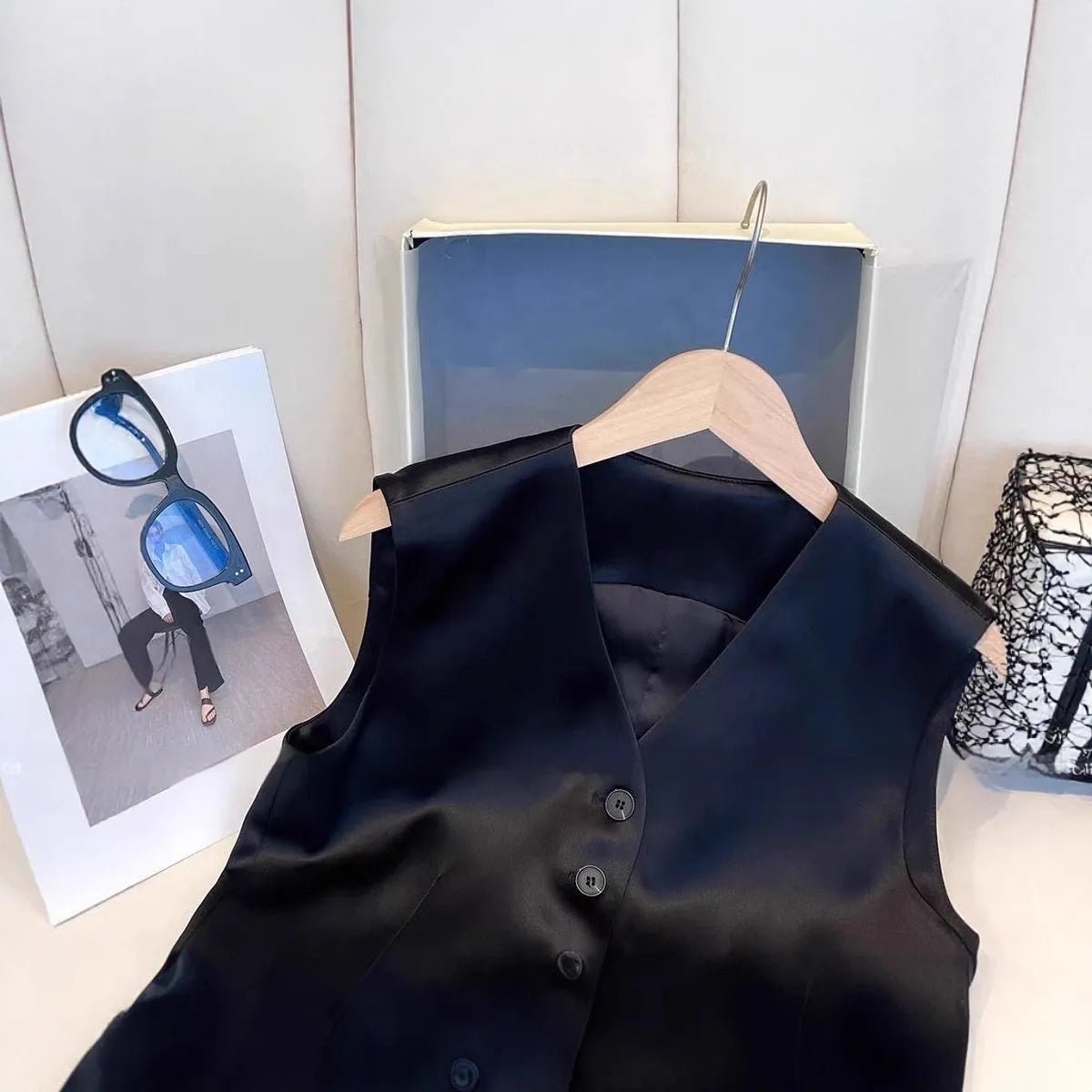 Black satin sleeveless vest for women on a hanger, showing loose fit and V-neck.