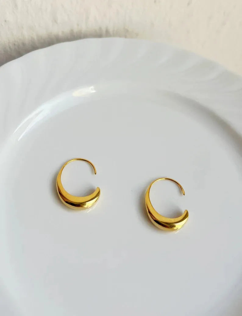 Gold electroplated alloy snake design drop earrings on a neutral background