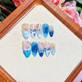 Set of blue transparent false nails with hand-painted carved design, showing sizes XS, S, M, L