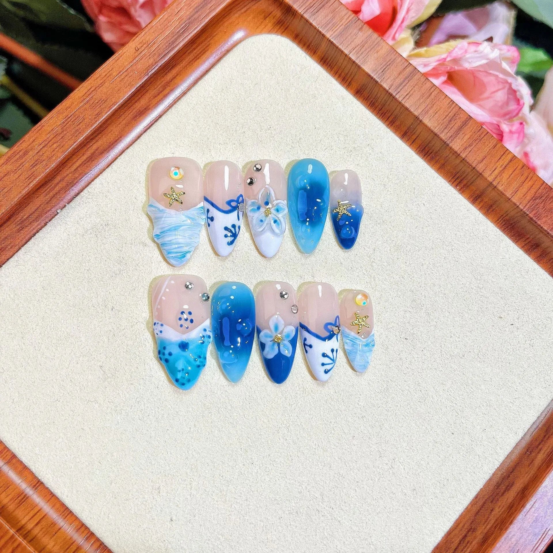 Set of blue transparent false nails with hand-painted carved design, showing sizes XS, S, M, L