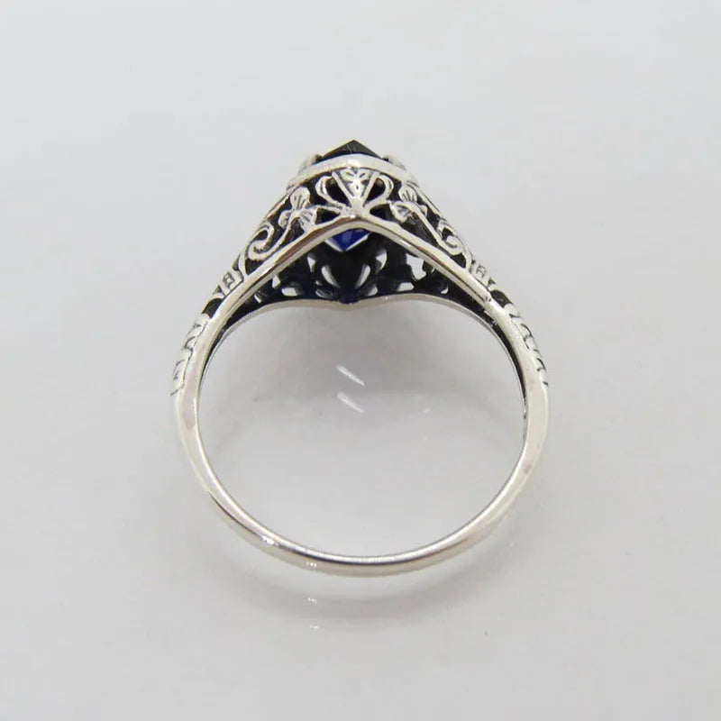 Women's silver alloy ring with geometric hollow design and central zircon stone, on a plain background