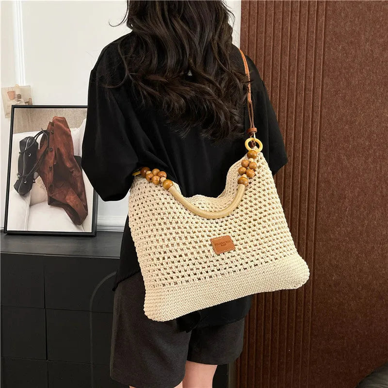 Knitted large capacity tote beach bag in bucket shape with contrast stitching and crossbody strap, black colour, on a plain background
