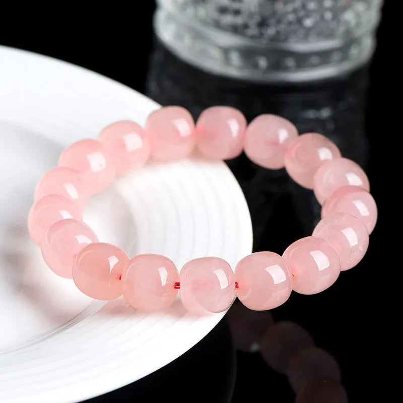 Pink natural crystal barrel bead bracelet with geometric shape on wrist.