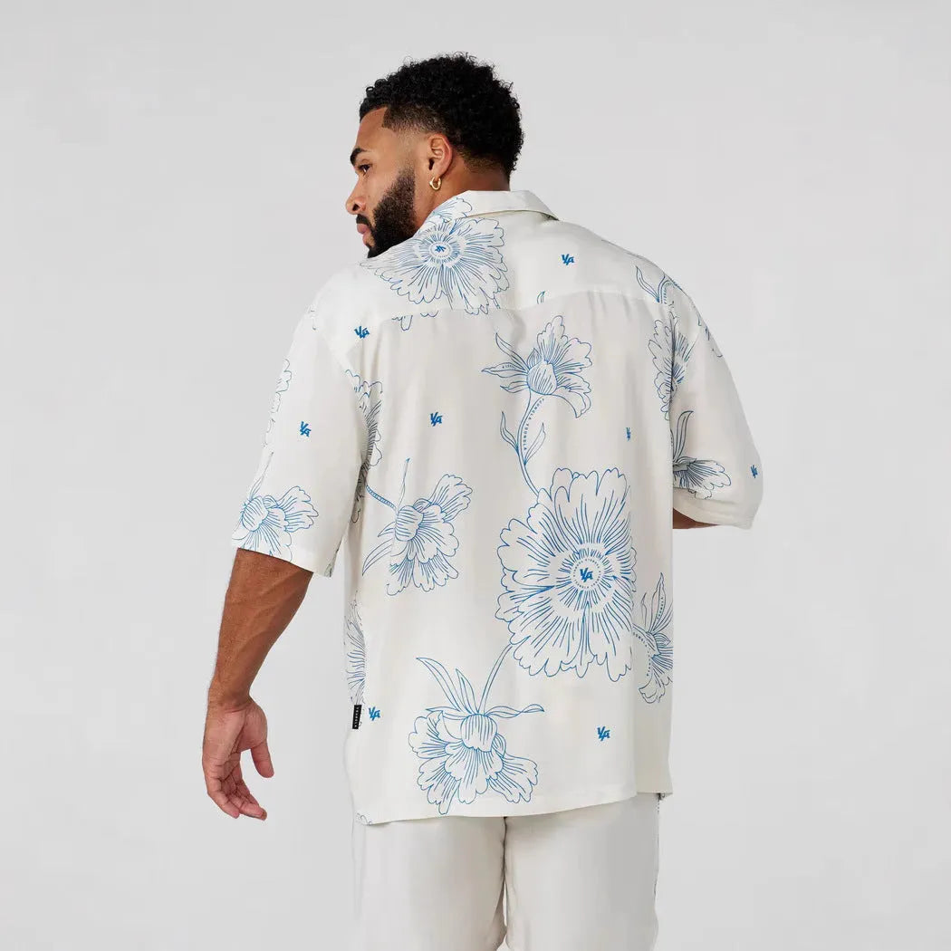 Man wearing a loose grey short-sleeve top with a floral print pattern