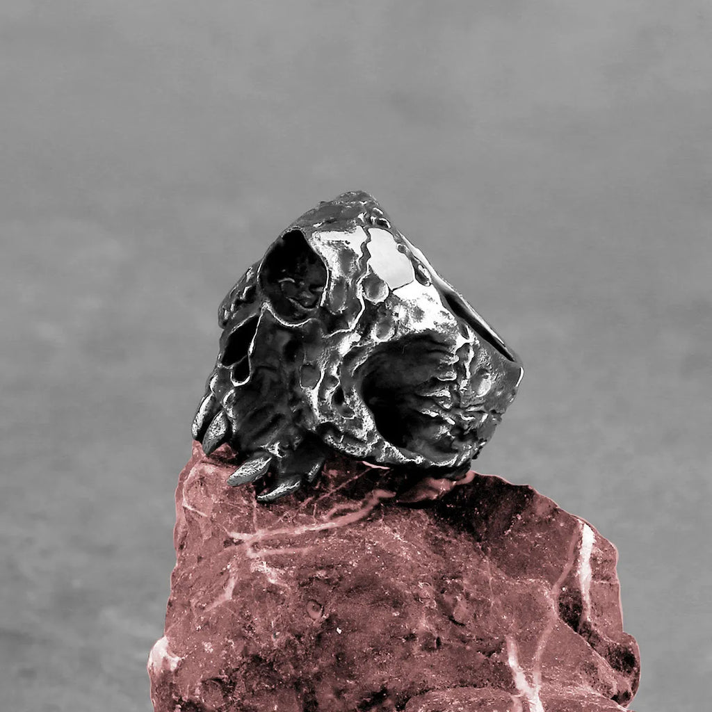 Close-up of a silver-toned alloy ring featuring a detailed one-eyed skull design on a finger.