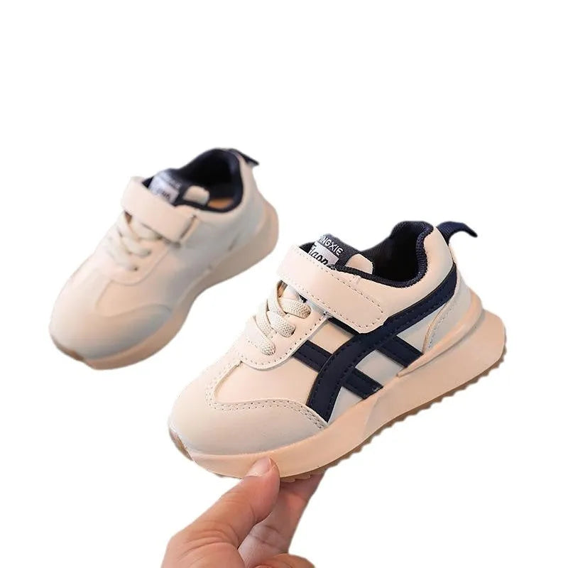 Children's white velcro sneaker with synthetic leather upper and rubber sole on a neutral background.