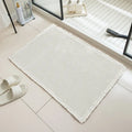 Checkered pattern non-slip polyester bathroom mat in beige colour on tiled floor.
