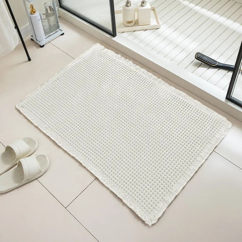 Checkered pattern non-slip polyester bathroom mat in beige colour on tiled floor.