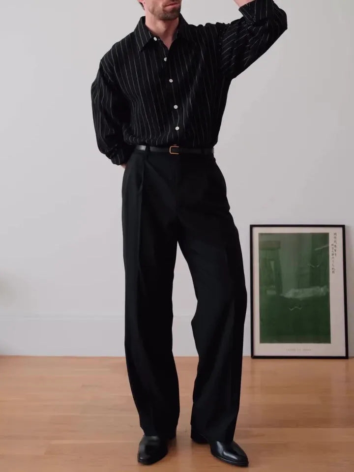 Man wearing a black pinstriped button-down long sleeve shirt with a collar.