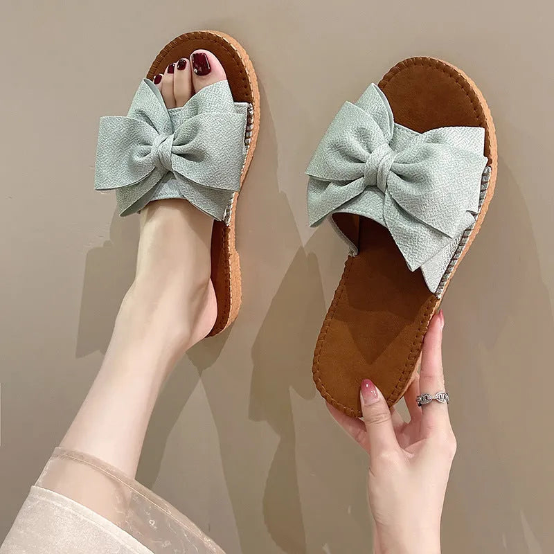 Women's slip-on suede sandals with bow, soft flat heel, beige colour, on casual setting