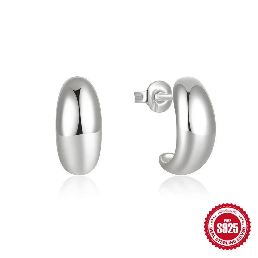 Glossy gold and silver tone C-shaped sterling silver stud earrings on a plain background.