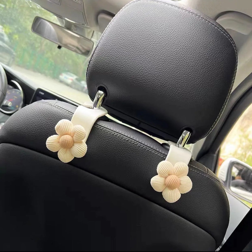 Plastic car seat hook in white, 11 by 5.5 cm, hanging from a headrest
