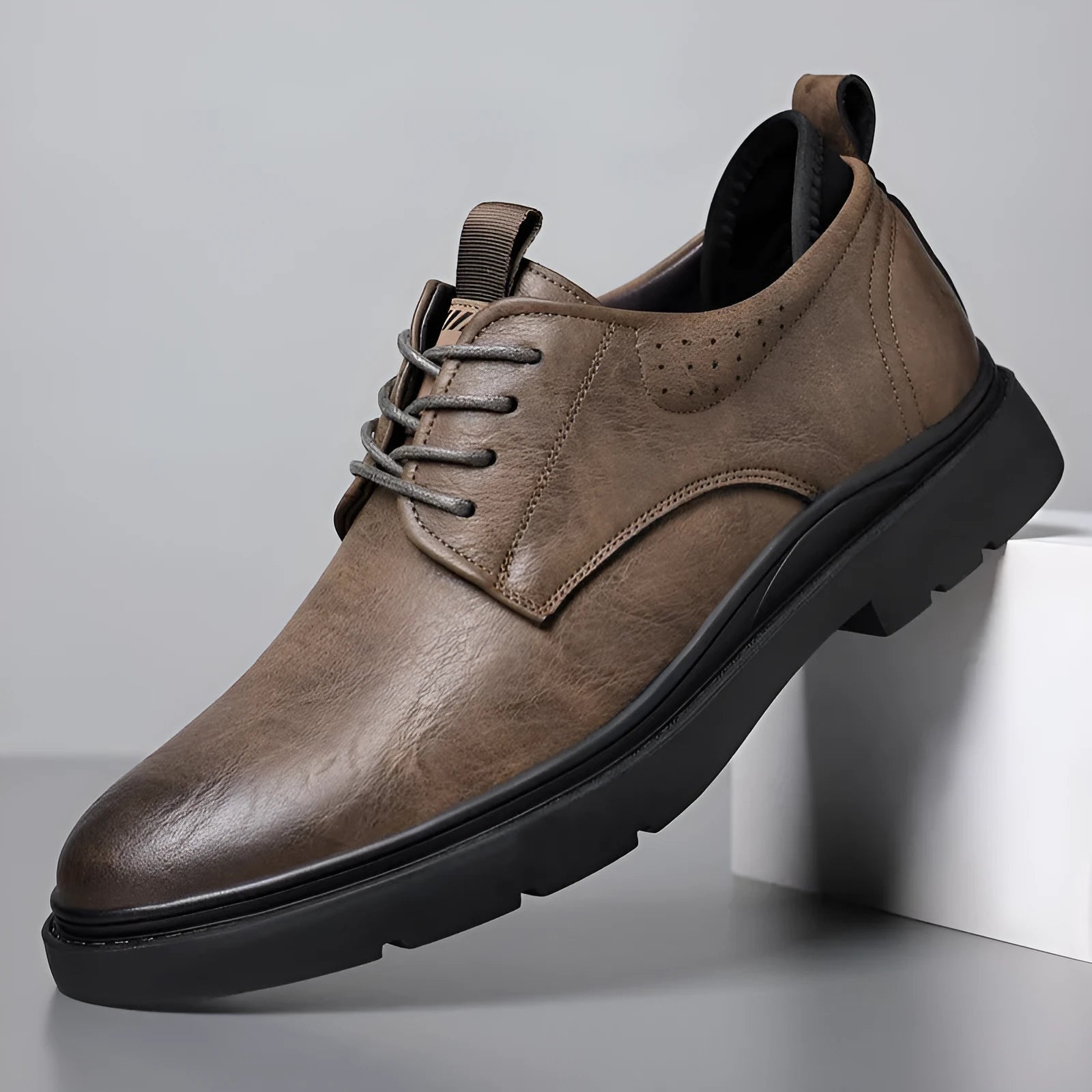 Men's black and brown leather shoes with rubber sole and sewn detailing on a white background.