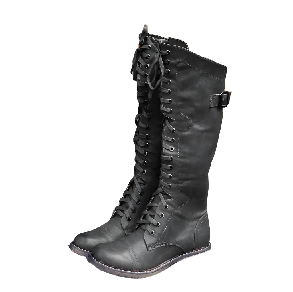Women's black cross strap knight ankle boots with front laces and side buckle on a solid colour background.