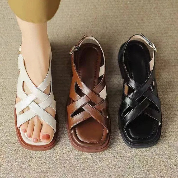Glossy black patent leather women's sandals with square toe and winding tape closure on a rubber sole.