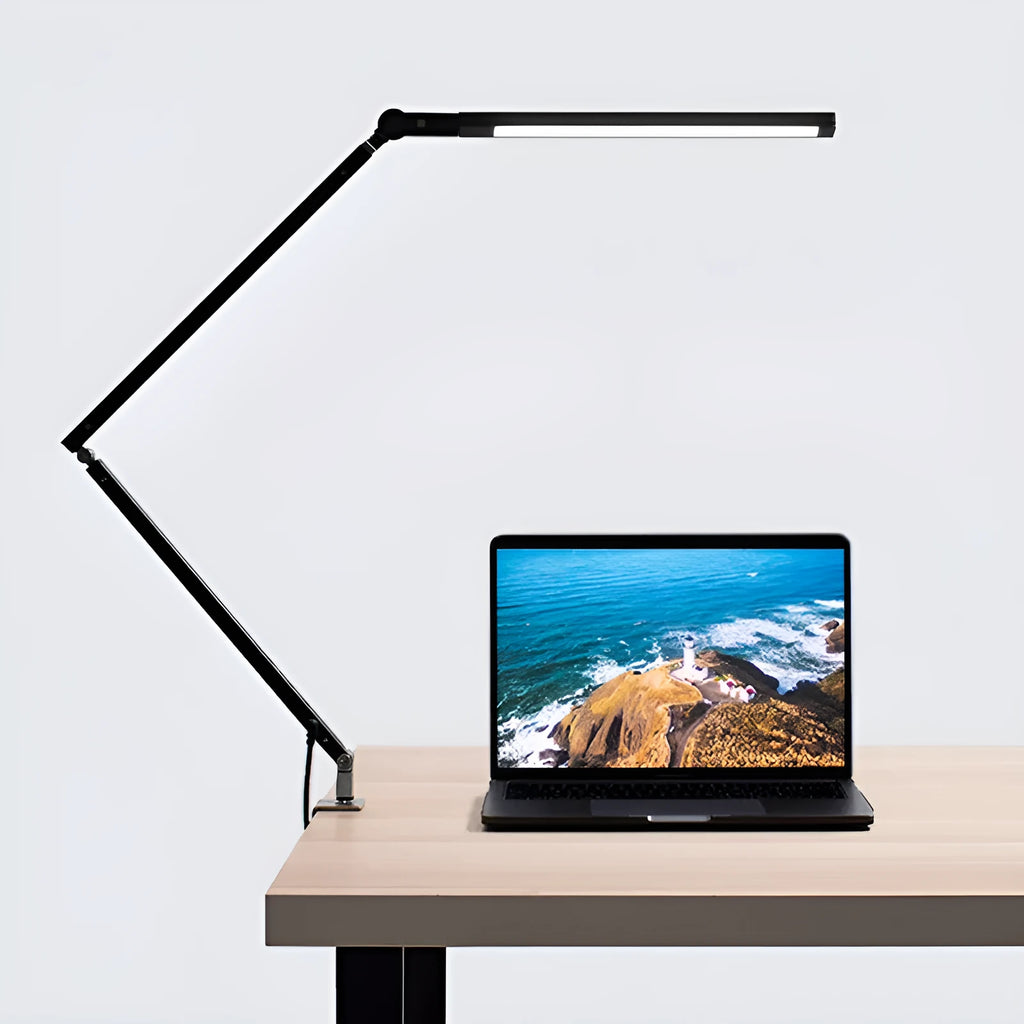 Black clip-on LED desk lamp with remote control attached to a desk edge, showing its folding arm.