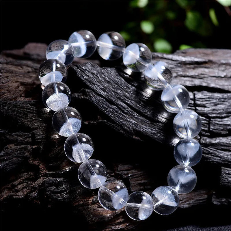 Close-up of a women's white crystal ghost pyramid bracelet with a Ruyi charm on a wrist.