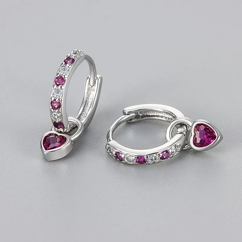 Women's heart-shaped clip-on earring with coloured gemstone centre on a gold-coloured metal setting.