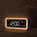 Blue rectangular LED atmosphere light alarm clock with digital display on a wooden desk.