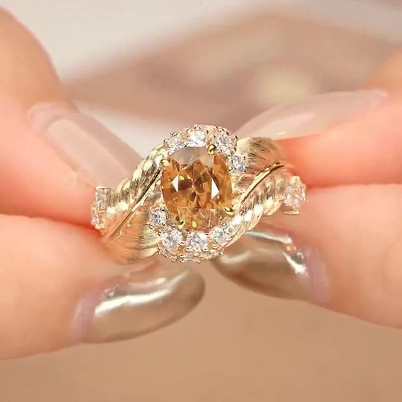 Yellow gold colour women's ring with an embossed feather design and a small inlaid zircon stone.