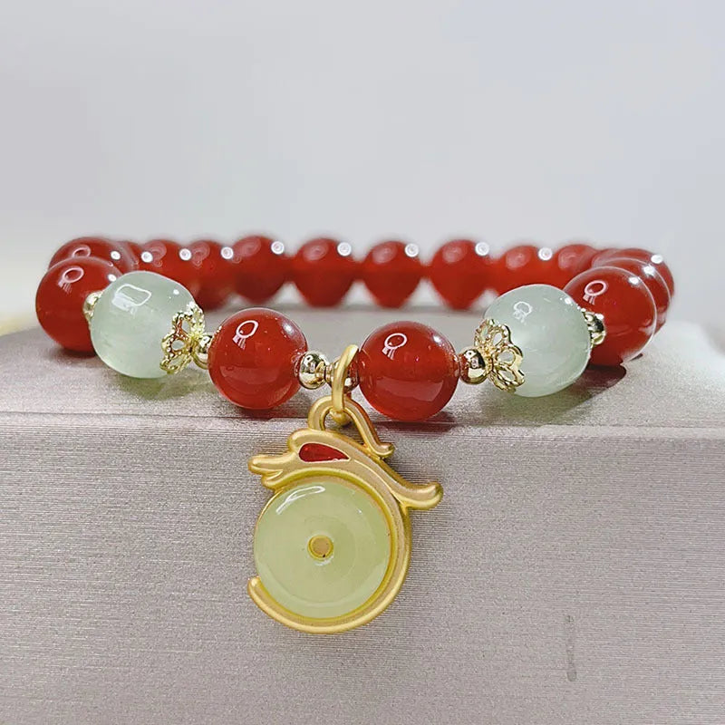 Handmade red agate bracelet with dragon motif and lucky charm beads.